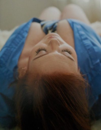 A woman wearing a shirt and a tie, lying on her back, the top of her head closest to the viewer