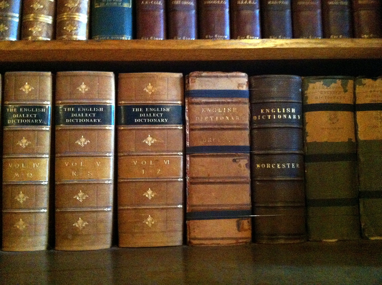 Old dictionaries on a shelf for post about come vs. cum